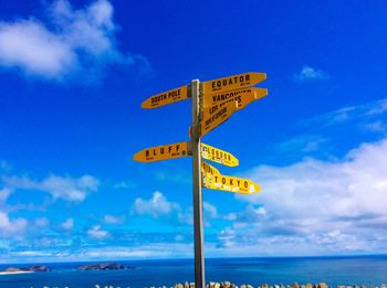 Information sign by sea against blue sky