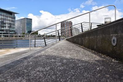 Empty road by buildings against sky