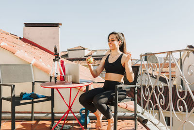 Young sporty fit woman coach doing online lessons through video call on her mobile phone 