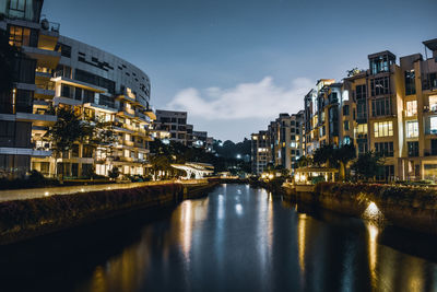 Canal amidst illuminated buildings in city at night