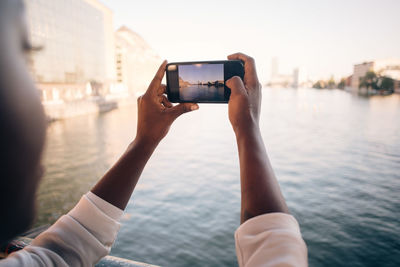 Midsection of man photographing with mobile phone in water