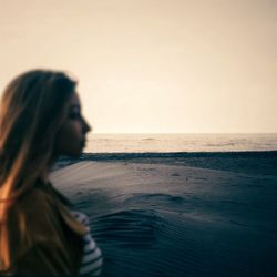 Woman on beach against sky during sunset