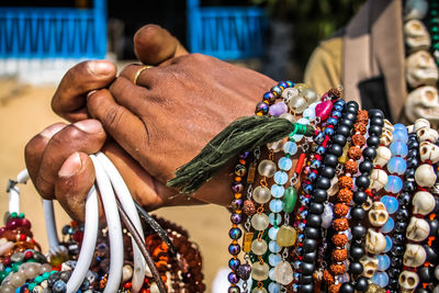 Cropped hand of man selling bead necklaces at beach