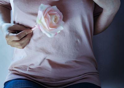 Midsection of person holding rose in hand