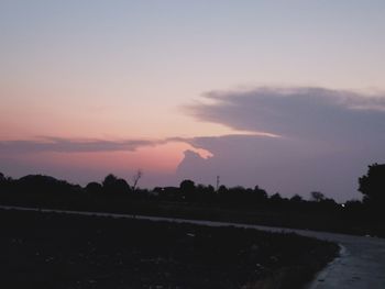 Silhouette trees on field against sky at sunset