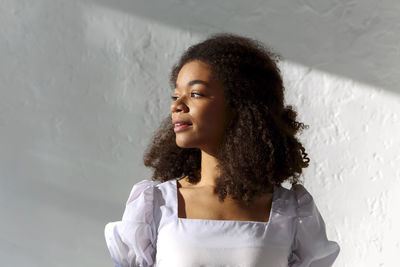 Young woman standing against wall