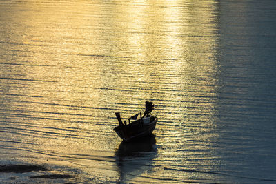 Silhouette man in boat sailing on sea against sky