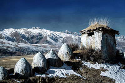 Traditional windmill on snowcapped mountain against sky
