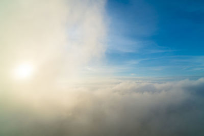 Low angle view of sunlight streaming through clouds