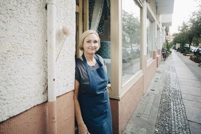 Portrait of confident female owner standing at entrance of upholstery workshop