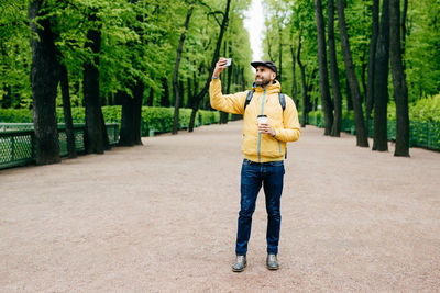 Full length of young man photographing on mobile phone