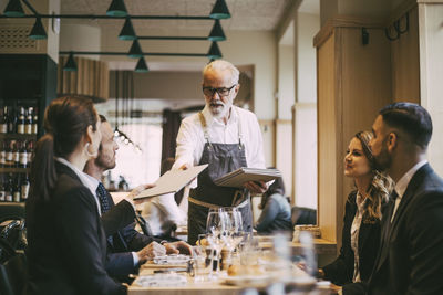 Waiter giving menu to business people in restaurant