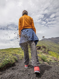 Rear view of man standing on land against sky