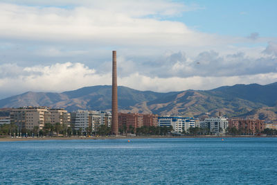 Sea by buildings against sky in city