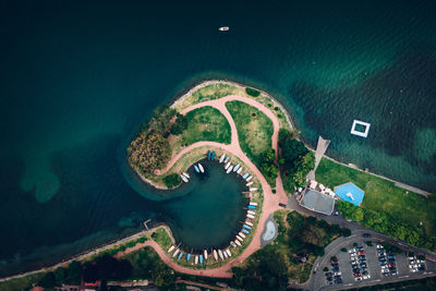 Melide coast with green trees and boats and a parking lot with the drone looking like a monster