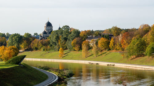 Scenic view of river by buildings against sky during autumn