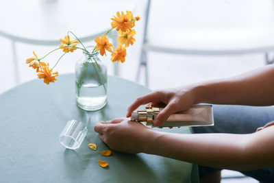 Cropped hands of woman holding bottle with flowers