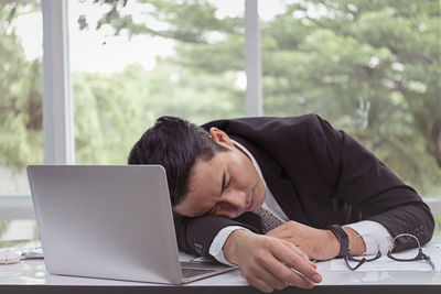 Rear view of man using mobile phone on table