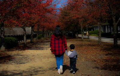 Full length of friends walking on footpath during autumn