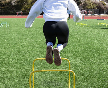 Low section of woman jumping over hurdles on turf