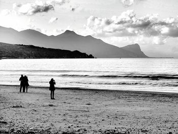 Silhouette of people on beach against sky