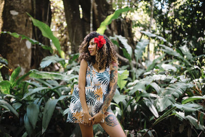 Young woman standing against plants in forest