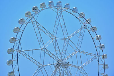 Low angle view of ferris wheel against clear blue sky