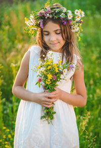 Girl wearing floral crown holding flowers