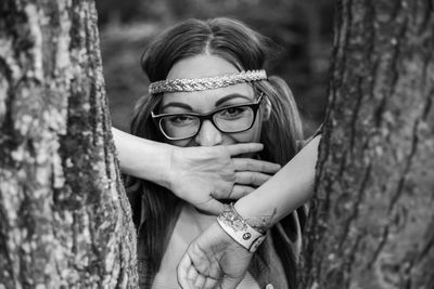 Portrait of woman wearing mask against tree trunk