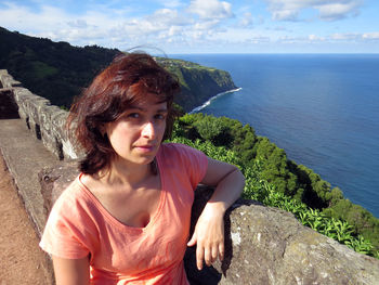 Woman standing by retaining wall against sky