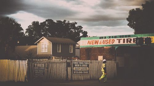 Information sign on street by building against sky