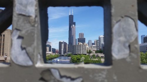 River against willis tower amidst buildings in city seen through railing