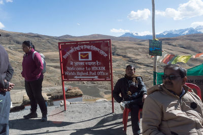 Rear view of people standing on road against sky