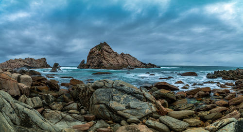 Scenic view of rocks on beach against sky