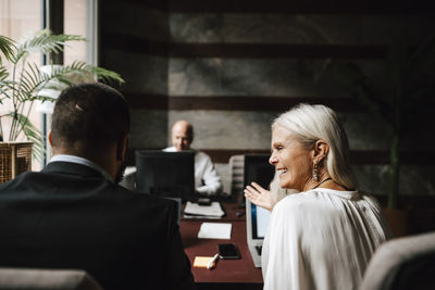 Cheerful female financial advisor discussing with male colleague at law office