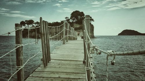 Wooden pier on sea against sky