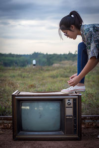 Woman wearing shoe on old television set at farm