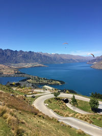 Scenic view of sea and mountains against clear blue sky