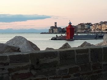 Sea by retaining wall against sky during sunset