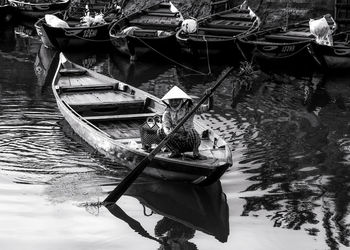 High angle view of man on boat moored at riverbank