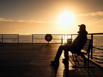 Tourist sit on wharf bench and enjoy misty sunny morning at sea. smooth water level. vivid effect