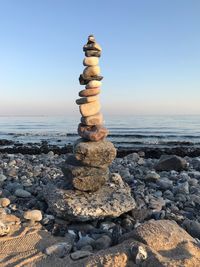 Stack of stones on beach against clear sky