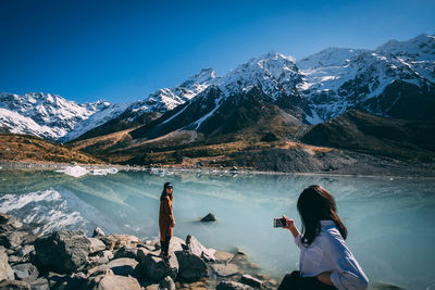 Rear view of people on snowcapped mountains against sky