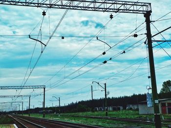 Railroad tracks by electricity pylon against sky