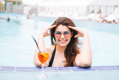 Stylish woman plus size body positive in black swimsuit enjoying life with glass of cocktail in pool