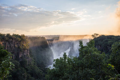 Scenic view of waterfall against sky during sunset