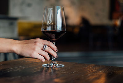 Close-up of woman holding red wineglass on table