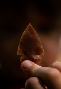 Close-up of hand holding ice cream cone against black background