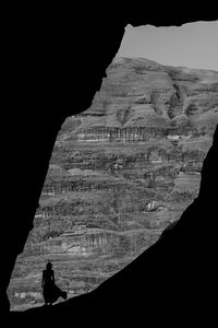 Silhouette of person on rock formation in cave