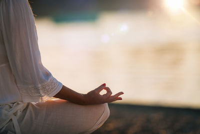 Sungazing. woman meditating by the lake, sitting in lotus position.